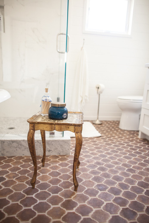 Design ideas for a mid-sized country bathroom in Los Angeles with raised-panel cabinets, white cabinets, a freestanding tub, a corner shower, a one-piece toilet, white walls, cement tiles, an undermount sink, marble benchtops, brown floor and a hinged shower door.