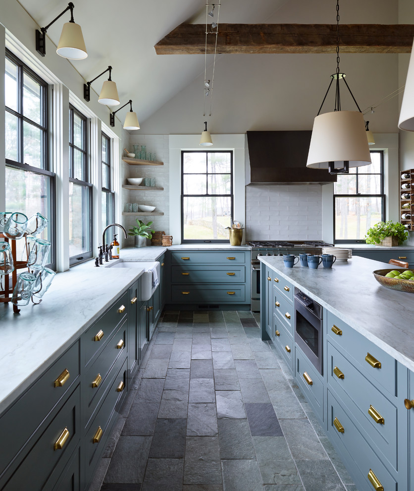 Inspiration for a mid-sized transitional l-shaped separate kitchen in Boston with a farmhouse sink, shaker cabinets, blue cabinets, quartzite benchtops, white splashback, subway tile splashback, stainless steel appliances, slate floors, with island, grey floor and white benchtop.