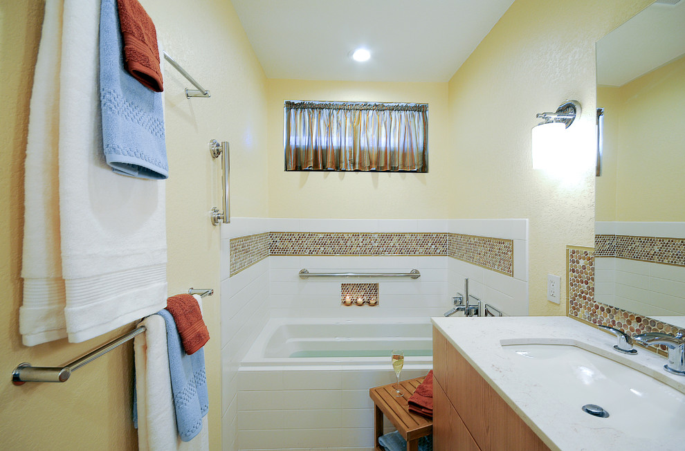 This is an example of a mid-sized transitional master bathroom in San Diego with an undermount sink, flat-panel cabinets, medium wood cabinets, engineered quartz benchtops, a drop-in tub, a curbless shower, a one-piece toilet, white tile, subway tile, yellow walls and ceramic floors.