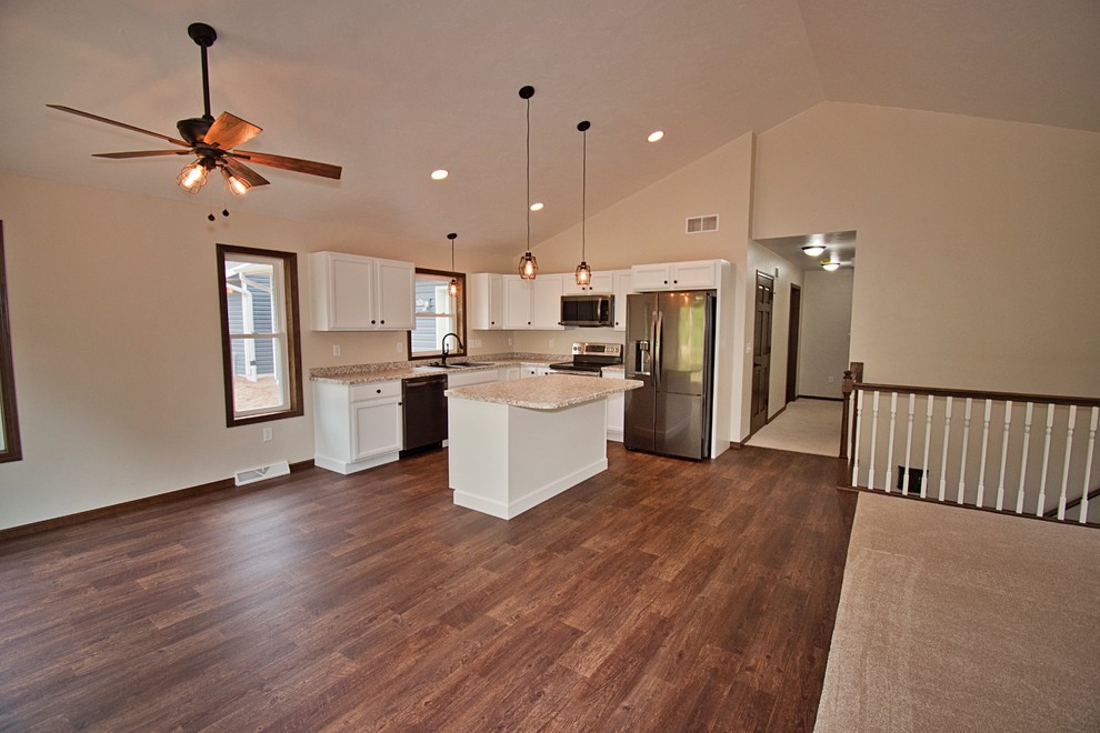 Open concept kitchen - mid-sized transitional l-shaped medium tone wood floor and brown floor open concept kitchen idea with a double-bowl sink, recessed-panel cabinets, white cabinets, laminate countertops, stainless steel appliances, an island and beige countertops