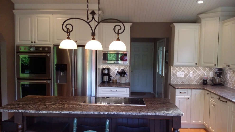 Open concept kitchen - mid-sized transitional l-shaped medium tone wood floor and brown floor open concept kitchen idea with raised-panel cabinets, white cabinets, granite countertops, beige backsplash, stone tile backsplash, stainless steel appliances and an island
