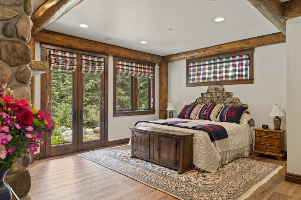 Large mountain style master exposed beam bedroom photo