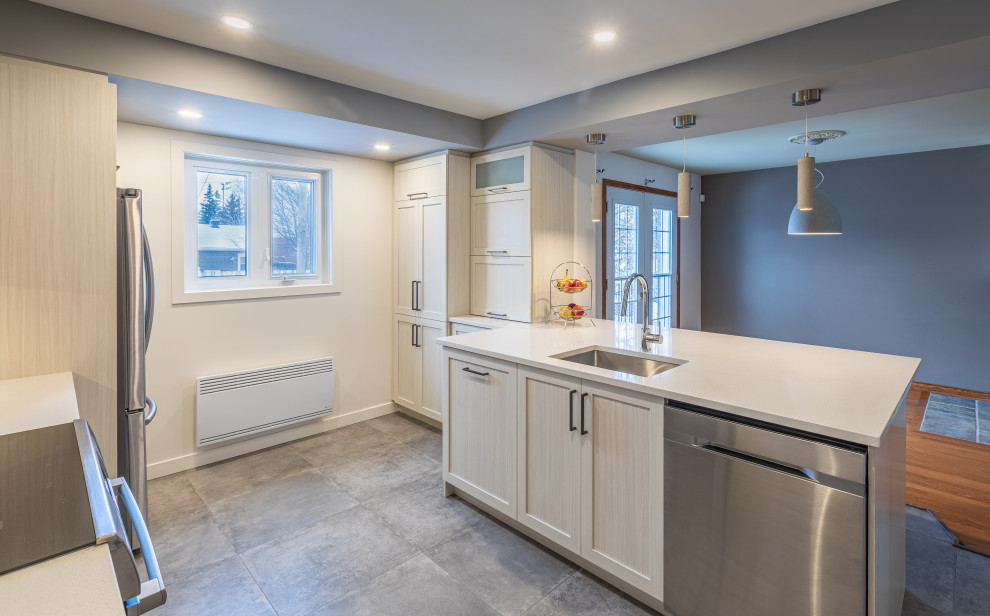 This is an example of a large contemporary galley open plan kitchen in Montreal with a single-bowl sink, shaker cabinets, beige cabinets, quartzite benchtops, grey splashback, brick splashback, ceramic floors, with island, grey floor and white benchtop.