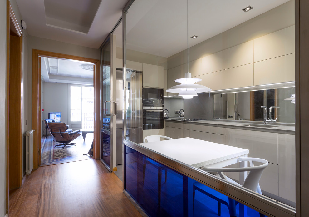 This is an example of a mid-sized contemporary l-shaped separate kitchen in Barcelona with a single-bowl sink, flat-panel cabinets, white cabinets, stainless steel appliances, no island and beige floor.