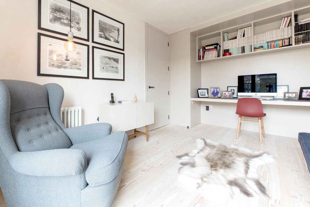 This is an example of a scandinavian study room in London with beige walls, light hardwood floors, a built-in desk and beige floor.