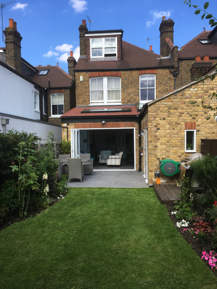 Design ideas for a mid-sized traditional backyard garden in London with with flowerbed and natural stone pavers.