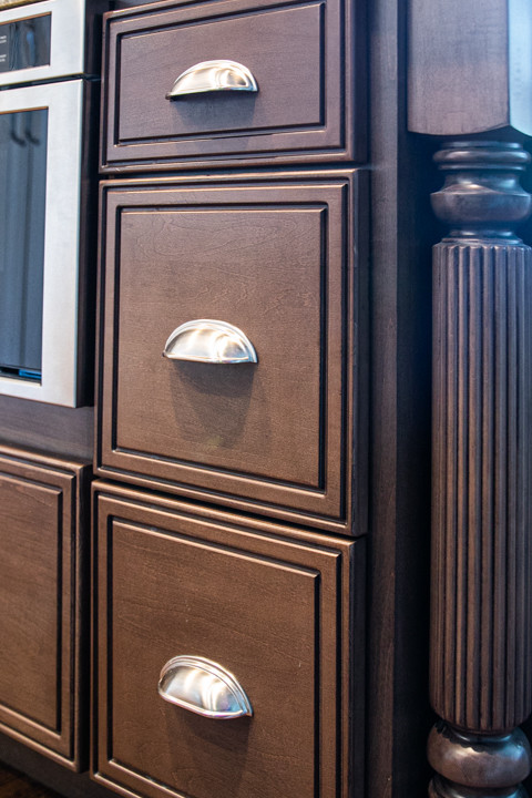 Large transitional l-shaped medium tone wood floor and brown floor open concept kitchen photo in Charlotte with a farmhouse sink, white cabinets, granite countertops, white backsplash, stainless steel appliances, an island, raised-panel cabinets, porcelain backsplash and white countertops