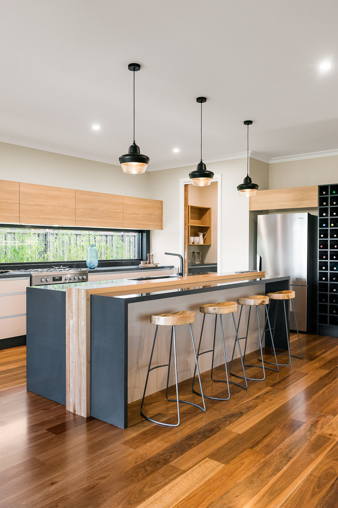 Design ideas for a mid-sized contemporary galley open plan kitchen in Other with an integrated sink, raised-panel cabinets, light wood cabinets, quartz benchtops, window splashback, stainless steel appliances, medium hardwood floors, with island and brown floor.