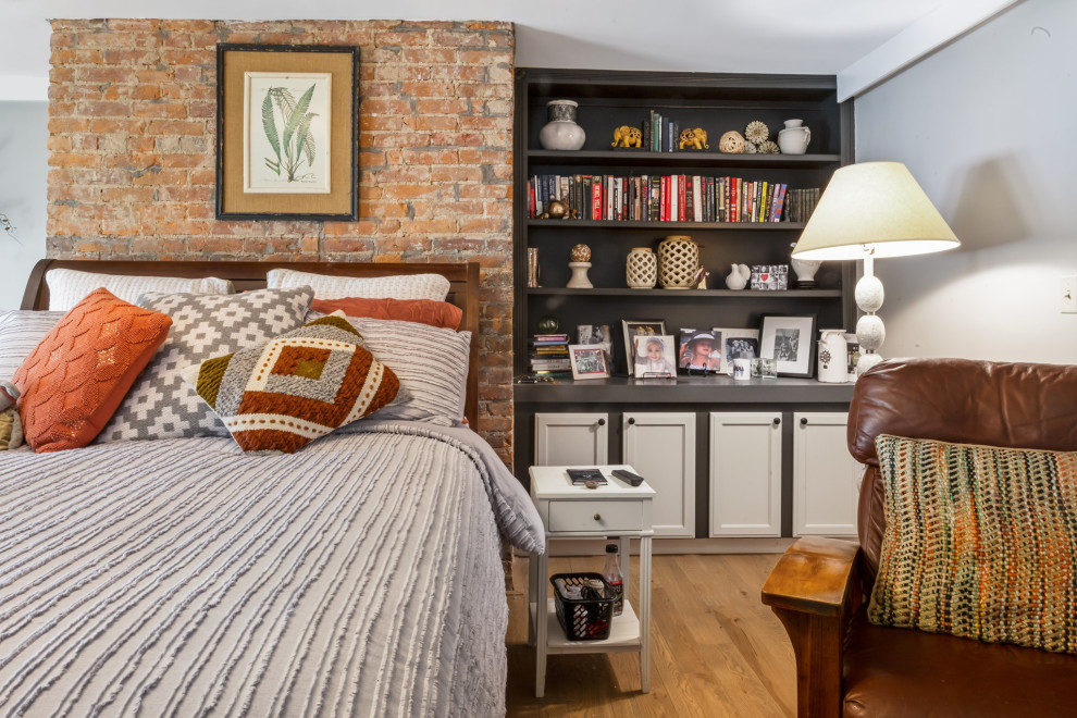 This is an example of a medium sized country master and grey and cream bedroom in Cincinnati with grey walls, medium hardwood flooring, beige floors and brick walls.