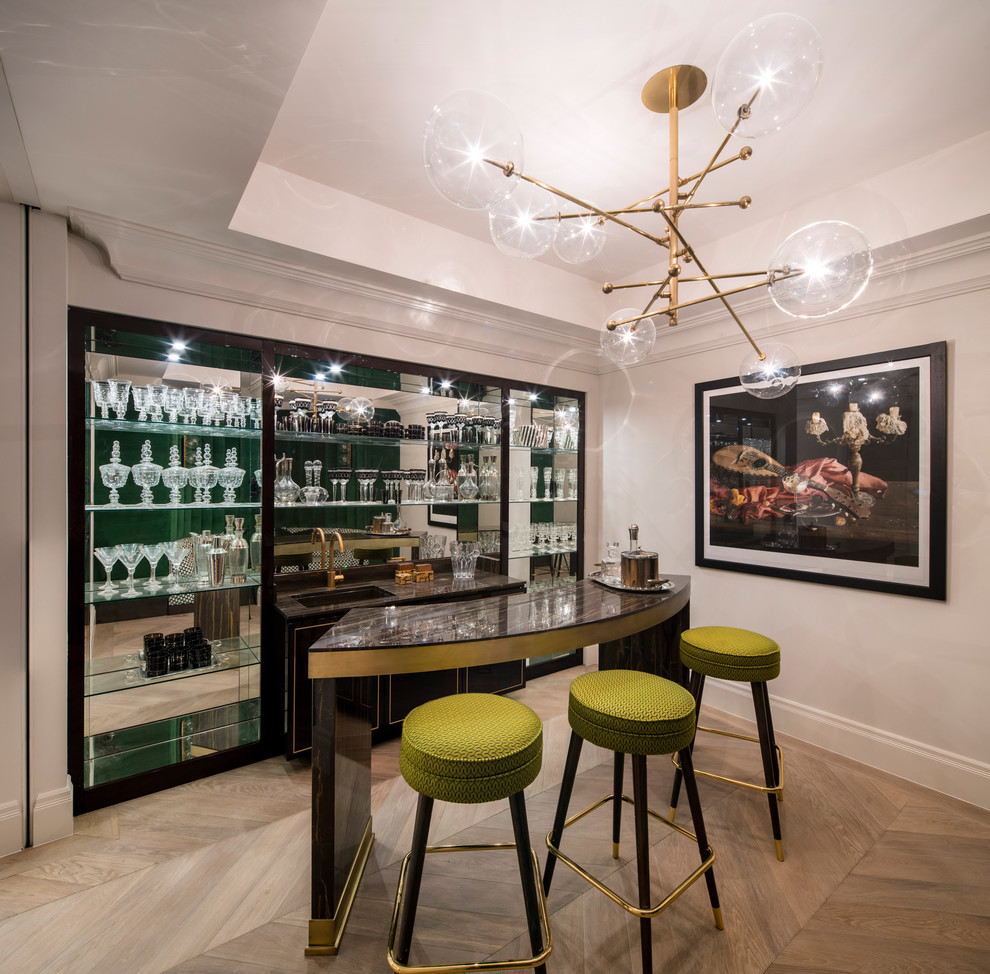 Contemporary single-wall wet bar in London with black cabinets, light hardwood floors, brown floor and mirror splashback.