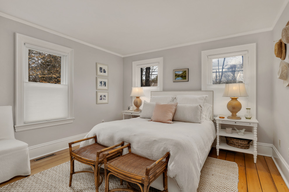 This is an example of a medium sized farmhouse guest bedroom in Boston with grey walls, light hardwood flooring, no fireplace and brown floors.
