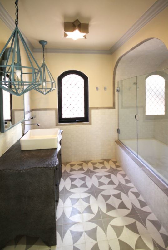 Mid-sized mediterranean master bathroom in Los Angeles with an alcove tub, an alcove shower, white tile, ceramic tile, beige walls, ceramic floors, a vessel sink, multi-coloured floor and a hinged shower door.