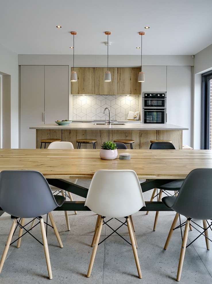 Inspiration for a mid-sized contemporary single-wall open plan kitchen in Belfast with a drop-in sink, flat-panel cabinets, beige cabinets, laminate benchtops, white splashback, ceramic splashback, black appliances, cement tiles, with island, grey floor and grey benchtop.