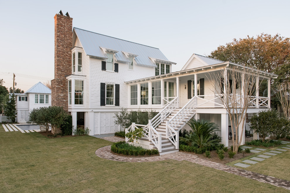 Photo of a beach style three-storey white house exterior in Charleston with wood siding, a gable roof and a metal roof.