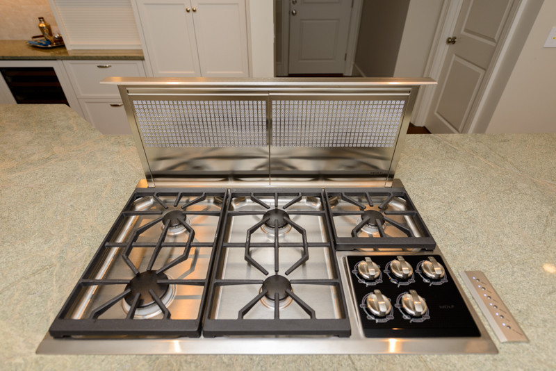 Transitional medium tone wood floor kitchen photo in Boston with a triple-bowl sink, recessed-panel cabinets, white cabinets, granite countertops, white backsplash, mosaic tile backsplash, stainless steel appliances and an island