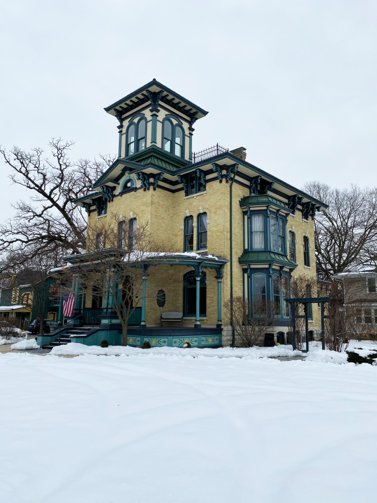 Design ideas for a large and beige victorian brick detached house in Milwaukee with four floors and a metal roof.