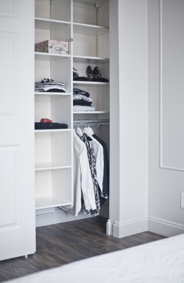 Photo of a small transitional gender-neutral built-in wardrobe in Seattle with flat-panel cabinets, white cabinets and light hardwood floors.