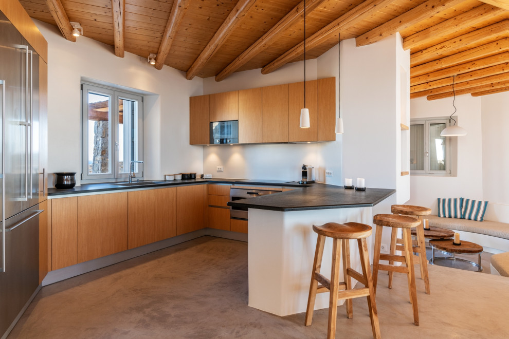 Beach style u-shaped kitchen in Other with an undermount sink, flat-panel cabinets, medium wood cabinets, a peninsula, grey floor, black benchtop, exposed beam and wood.
