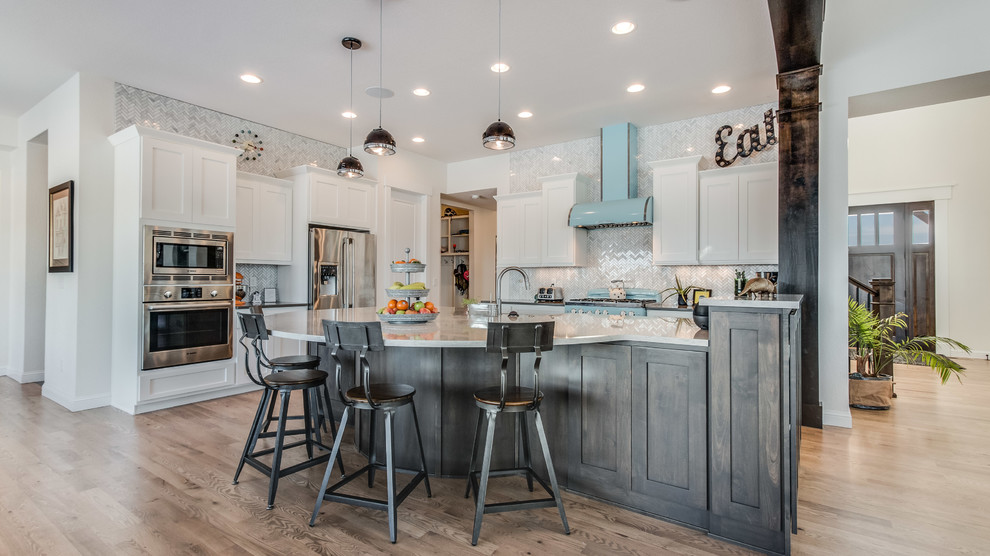 Large transitional l-shaped light wood floor open concept kitchen photo in Denver with a farmhouse sink, shaker cabinets, white cabinets, marble countertops, gray backsplash, matchstick tile backsplash, stainless steel appliances and an island