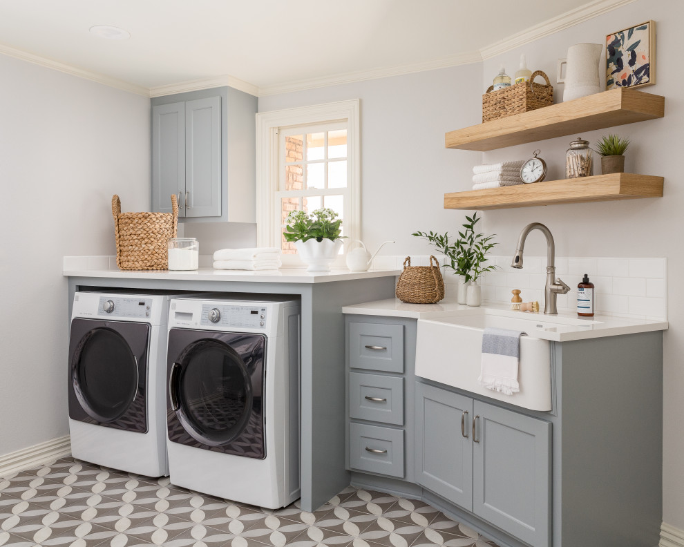 Design ideas for a transitional single-wall utility room in Houston with grey walls, a farmhouse sink, shaker cabinets, grey cabinets, white splashback, subway tile splashback, a side-by-side washer and dryer, multi-coloured floor and white benchtop.