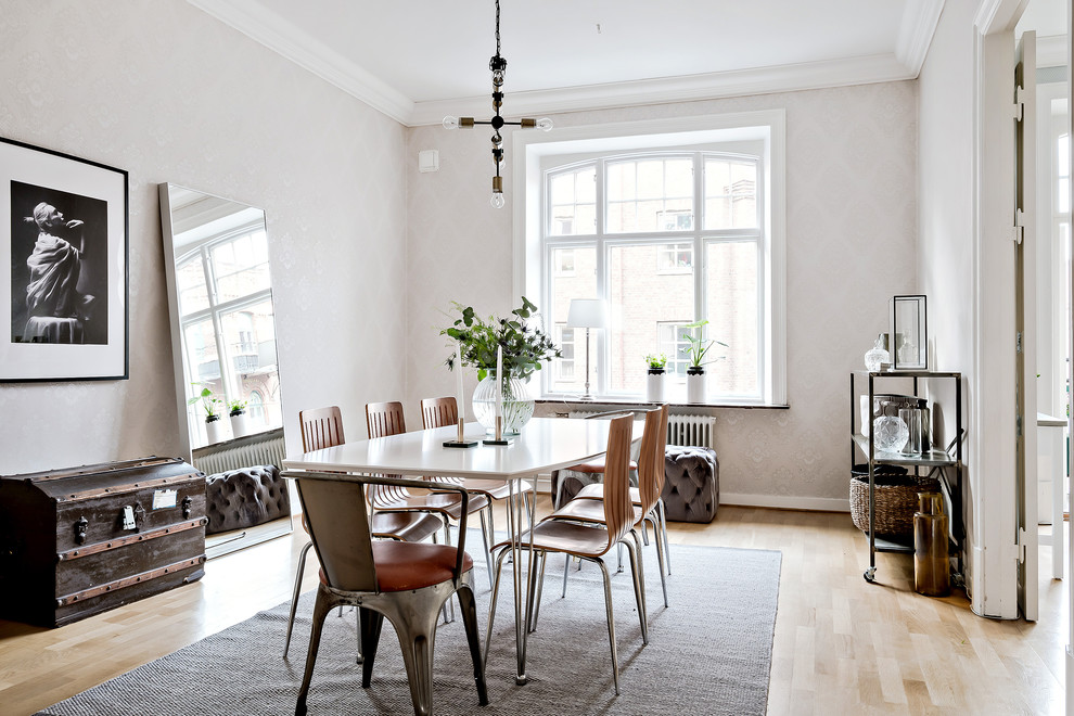 Scandinavian separate dining room in Gothenburg with white walls, light hardwood floors and beige floor.