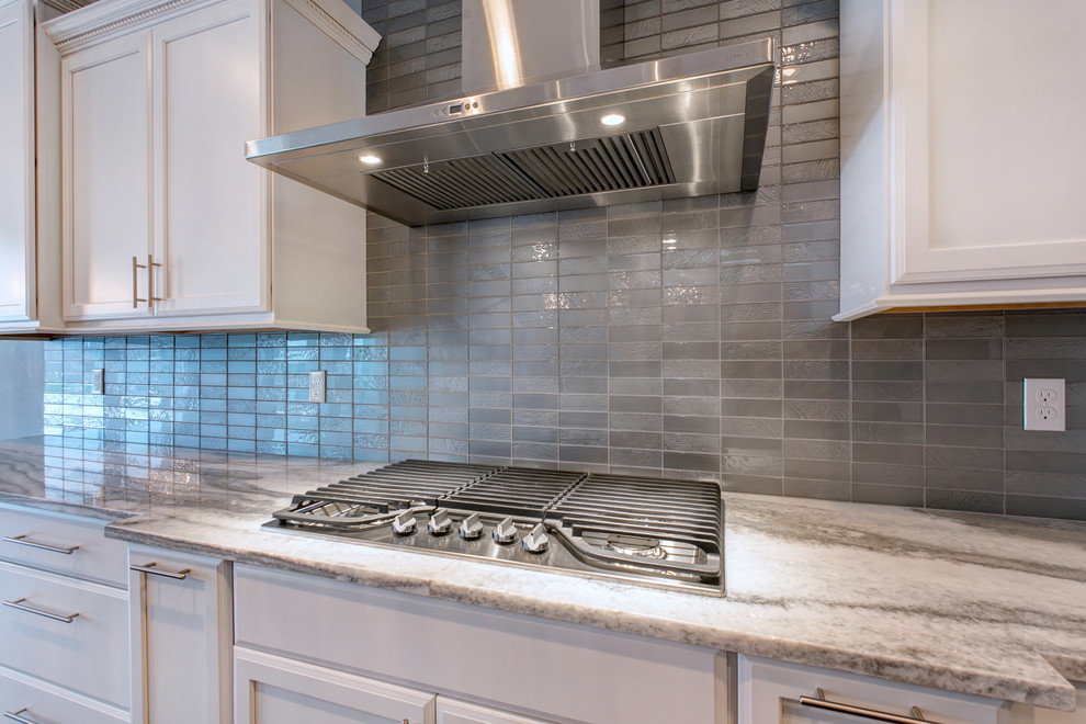 Example of a large transitional l-shaped dark wood floor open concept kitchen design in Seattle with an undermount sink, recessed-panel cabinets, white cabinets, granite countertops, gray backsplash, glass tile backsplash, stainless steel appliances and an island