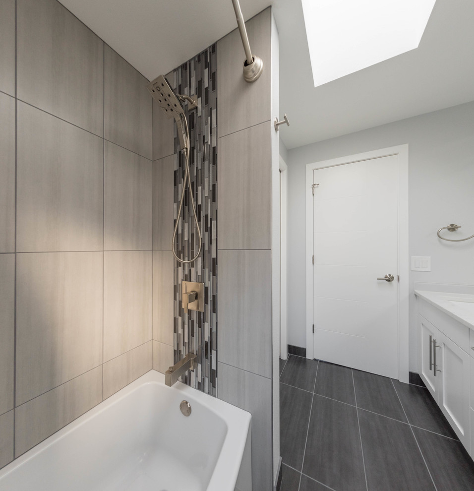 Photo of a small modern kids bathroom in Seattle with flat-panel cabinets, light wood cabinets, a drop-in tub, an open shower, a one-piece toilet, gray tile, ceramic tile, white walls, ceramic floors, an undermount sink, engineered quartz benchtops and grey floor.