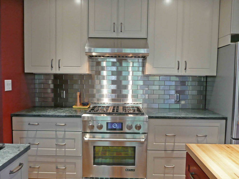 Transitional eat-in kitchen in DC Metro with raised-panel cabinets, white cabinets, metallic splashback, metal splashback and stainless steel appliances.