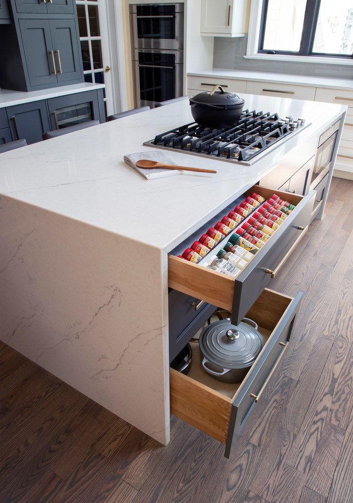 Kitchen - large transitional u-shaped medium tone wood floor kitchen idea with an undermount sink, gray cabinets, quartz countertops, gray backsplash, glass tile backsplash, stainless steel appliances, an island and white countertops