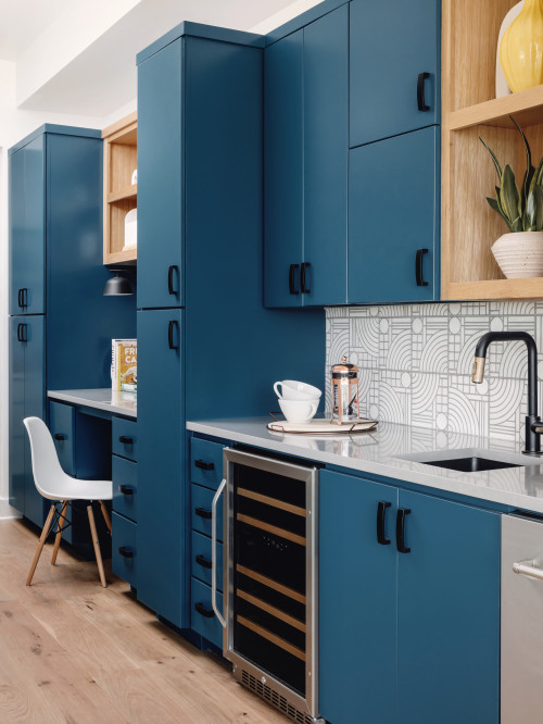 Modern bathroom cabinets in matte navy blue with black pulls, open oak shelves, patterned white tile backsplash, and an undermount sink.