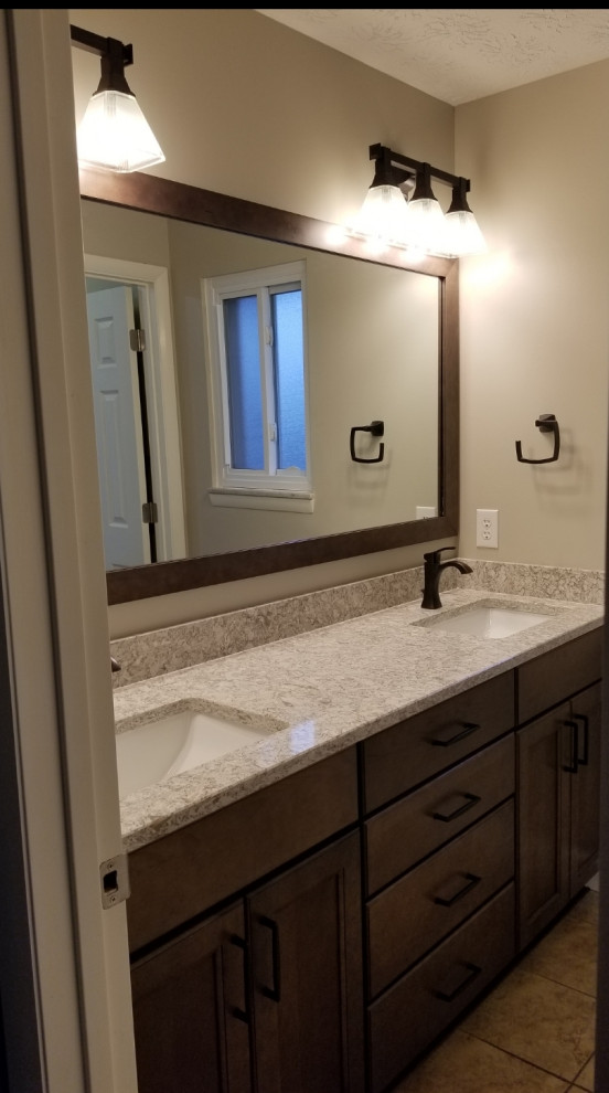 Klassisk inredning av ett mellanstort beige beige badrum med dusch, med luckor med infälld panel, bruna skåp, beige kakel, linoleumgolv, ett undermonterad handfat och bänkskiva i kvarts