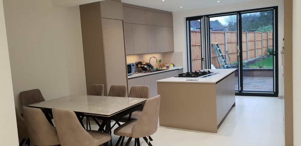 This is an example of a large contemporary galley eat-in kitchen in London with an integrated sink, flat-panel cabinets, grey cabinets, quartzite benchtops, white splashback, engineered quartz splashback, black appliances, porcelain floors, with island, white floor, white benchtop and recessed.