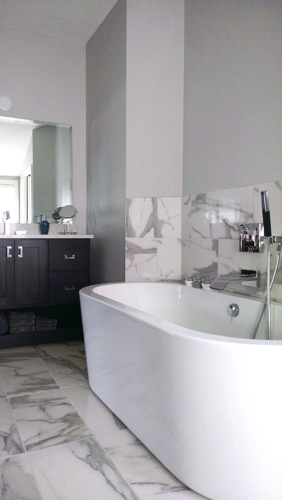 This is an example of a large modern master bathroom in Chicago with flat-panel cabinets, black cabinets, a freestanding tub, an alcove shower, a one-piece toilet, gray tile, marble, grey walls, mosaic tile floors, an undermount sink, granite benchtops, grey floor and a hinged shower door.