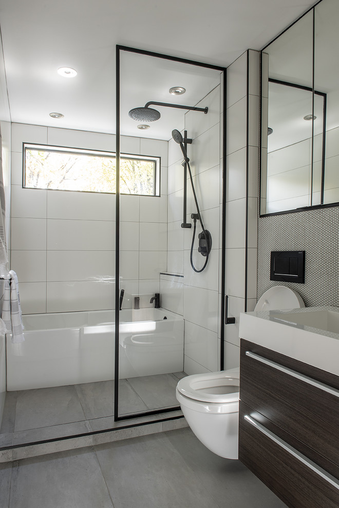 Photo of a small contemporary kids bathroom in Montreal with flat-panel cabinets, dark wood cabinets, an alcove tub, an open shower, a wall-mount toilet, white tile, ceramic tile, white walls, porcelain floors, a wall-mount sink, solid surface benchtops, grey floor, an open shower and white benchtops.