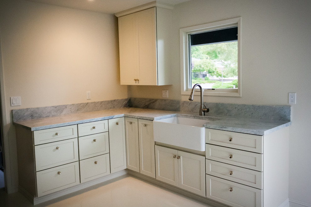 Example of a transitional kitchen design in San Francisco with a farmhouse sink, white cabinets and marble countertops