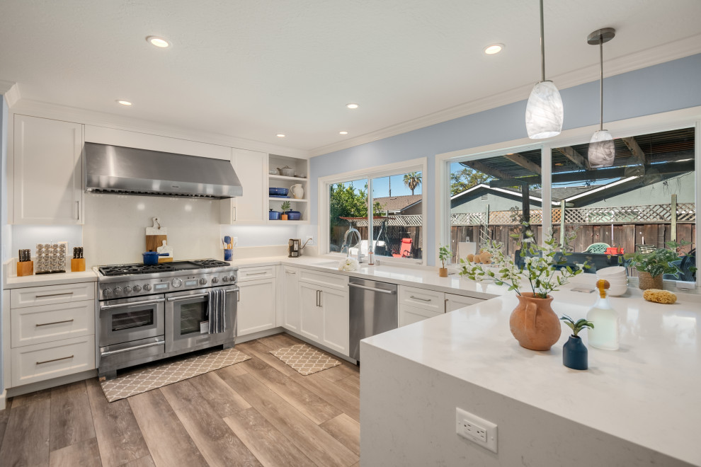 Design ideas for a mid-sized contemporary l-shaped eat-in kitchen in San Francisco with an undermount sink, shaker cabinets, white cabinets, quartzite benchtops, white splashback, porcelain splashback, stainless steel appliances, vinyl floors, a peninsula, brown floor and white benchtop.