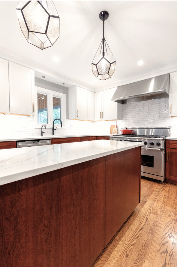 Inspiration for a mid-sized transitional medium tone wood floor kitchen remodel in Chicago with an undermount sink, shaker cabinets, quartz countertops, white backsplash, ceramic backsplash, stainless steel appliances, an island and white countertops