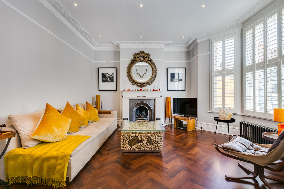 Photo of a mid-sized eclectic family room in London with grey walls, a standard fireplace, a metal fireplace surround, a freestanding tv, brown floor and dark hardwood floors.