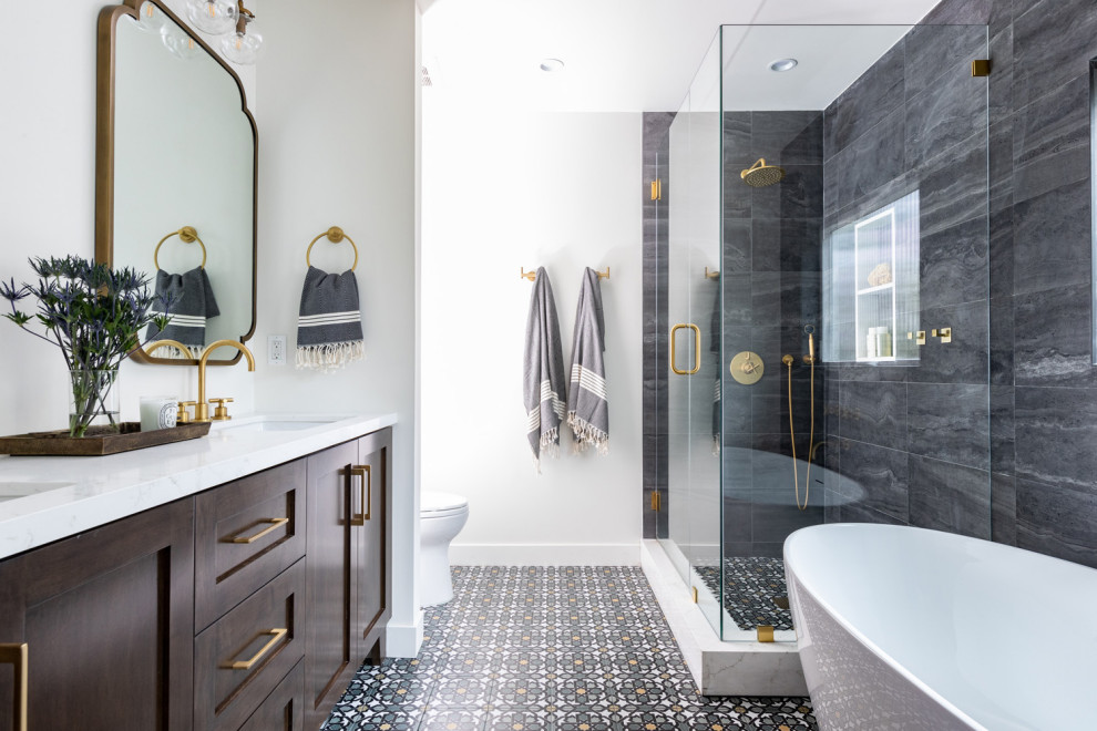 This is an example of a mid-sized transitional master bathroom in Los Angeles with shaker cabinets, brown cabinets, a freestanding tub, a one-piece toilet, black tile, porcelain tile, white walls, porcelain floors, an undermount sink, engineered quartz benchtops, green floor, a hinged shower door, white benchtops, a double vanity and a built-in vanity.