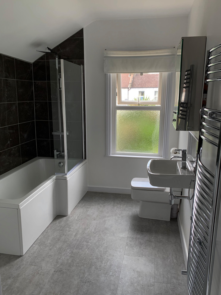 Mid-sized traditional kids bathroom in Surrey with a shower/bathtub combo, a one-piece toilet, gray tile, ceramic tile, white walls, vinyl floors, a wall-mount sink, grey floor and a single vanity.