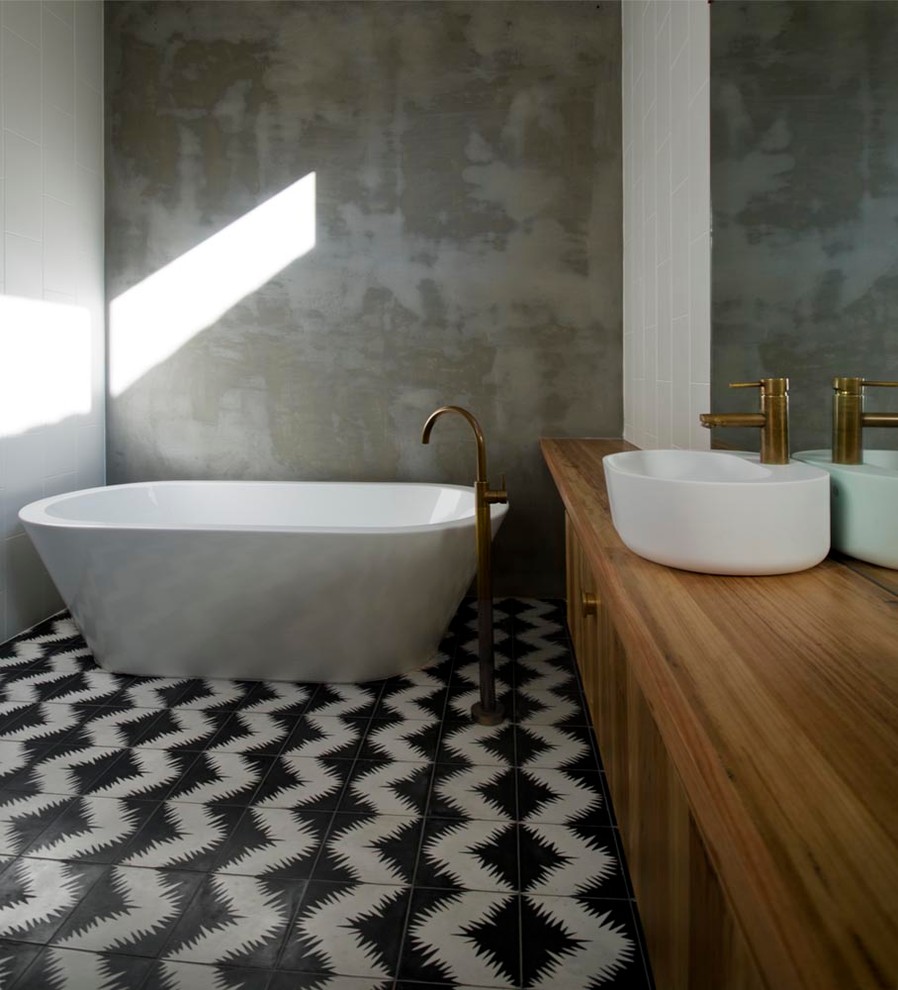 Design ideas for a mid-sized contemporary master bathroom in Melbourne with a vessel sink, flat-panel cabinets, medium wood cabinets, wood benchtops, a freestanding tub, cement tile, ceramic floors, grey walls and brown benchtops.