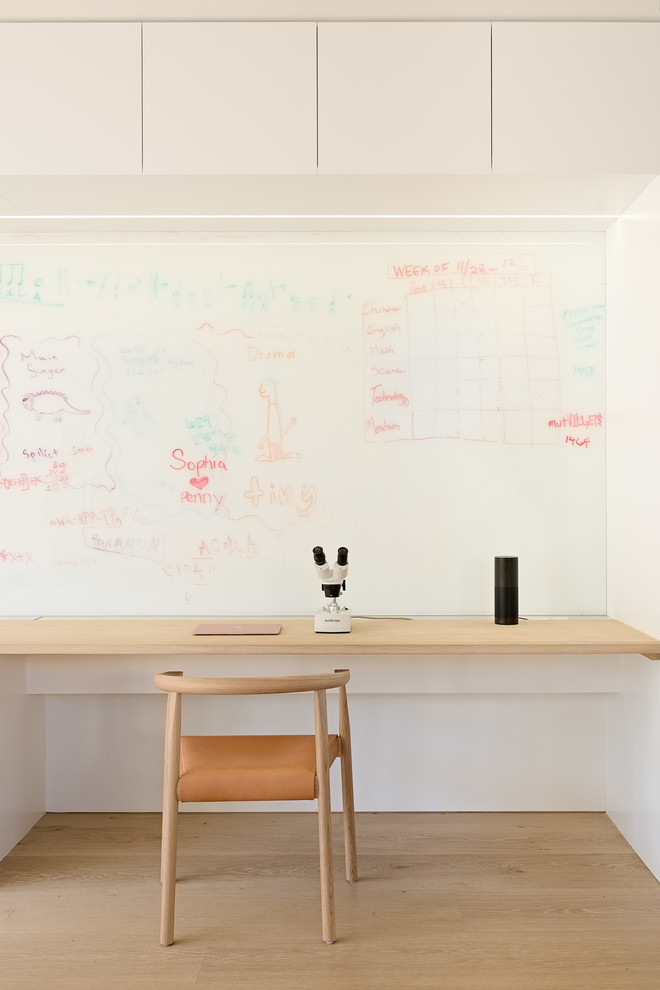 Inspiration for a mid-sized modern built-in desk light wood floor and beige floor study room remodel in San Francisco with white walls
