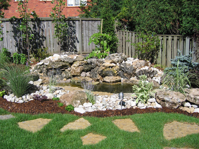 Inspiration for a transitional backyard stone water fountain landscape in Toronto with no cover.