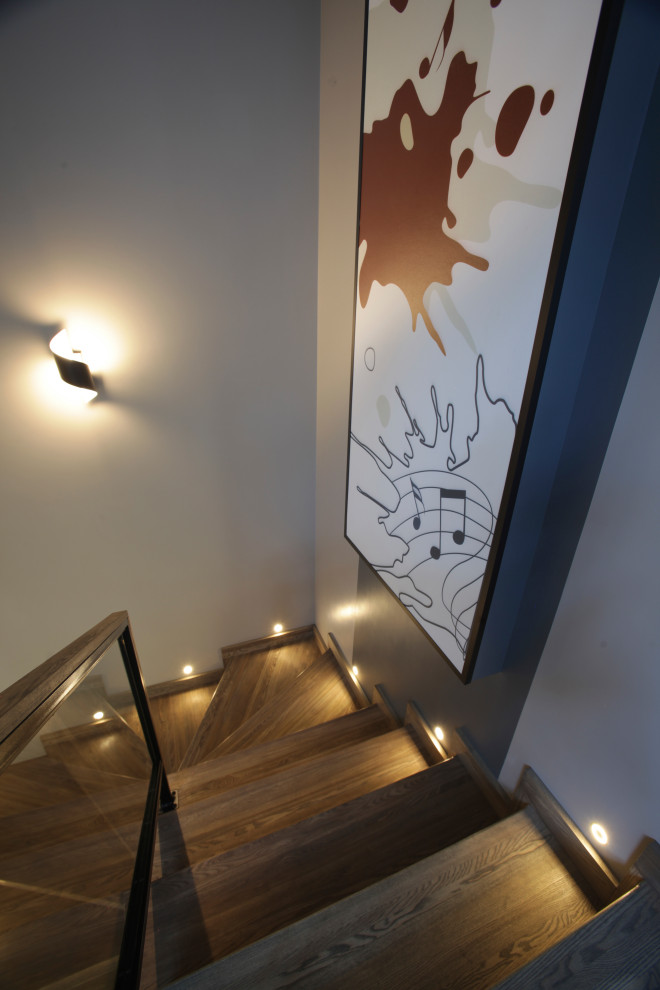 Imagen de escalera contemporánea con escalones de madera, contrahuellas de madera y barandilla de varios materiales