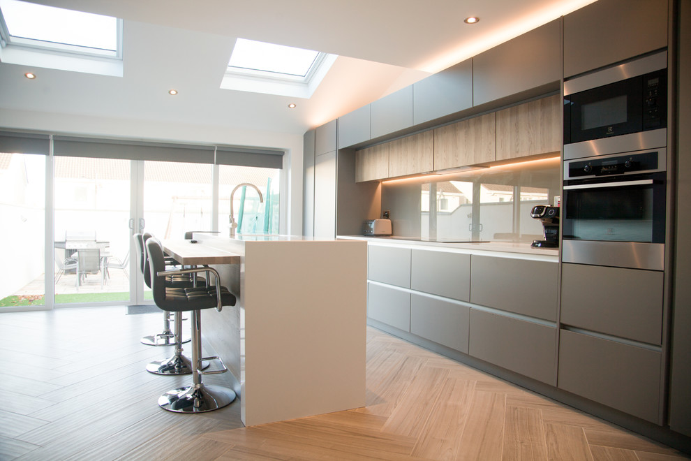 Contemporary open plan kitchen in Dublin with quartzite benchtops, porcelain floors, with island and beige floor.