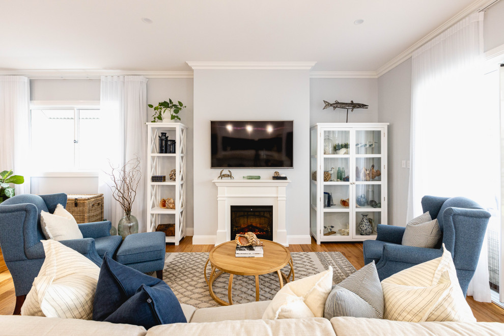 Пример оригинального дизайна: гостиная комната в стиле неоклассика (современная классика) с серыми стенами, паркетным полом среднего тона, стандартным камином, телевизором на стене и коричневым полом