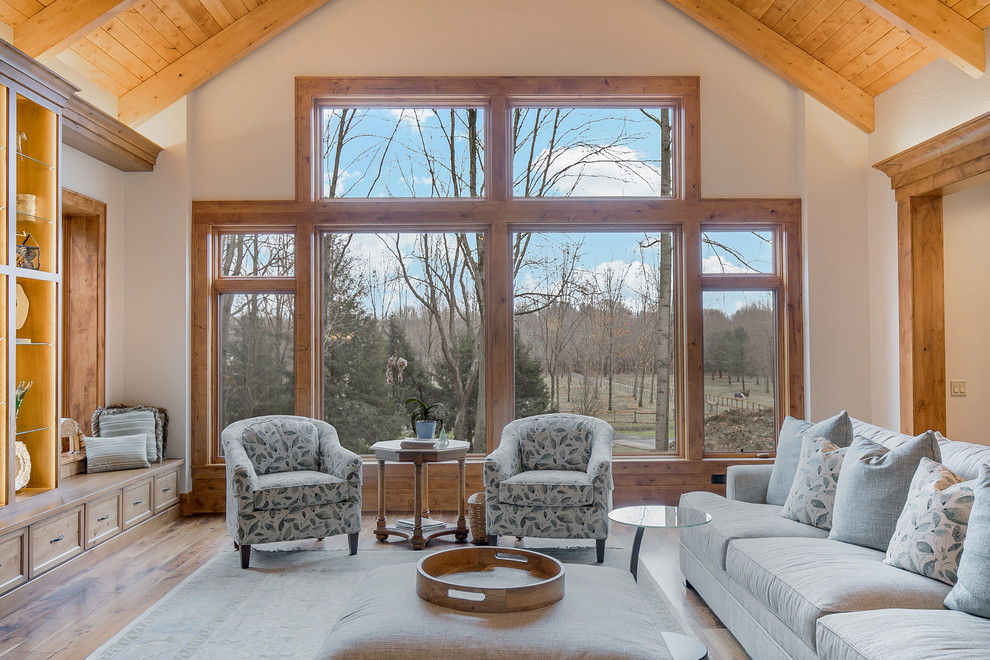 Photo of a large country open concept family room in Cleveland with white walls, medium hardwood floors, a standard fireplace, a stone fireplace surround and a freestanding tv.