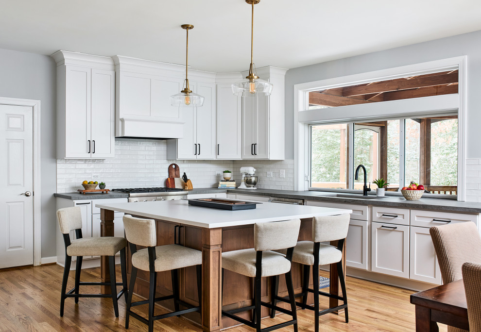 Photo of a mid-sized transitional eat-in kitchen in DC Metro with white cabinets, white splashback, subway tile splashback, light hardwood floors, with island and grey benchtop.