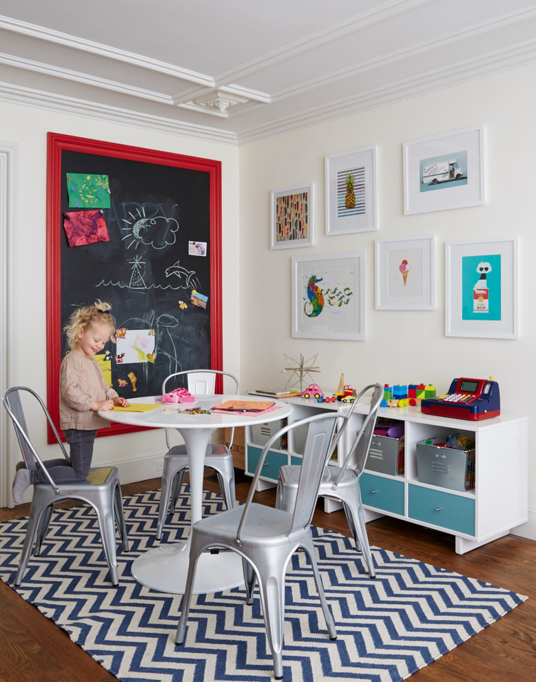 This is an example of a transitional gender-neutral kids' playroom in New York with white walls and medium hardwood floors.