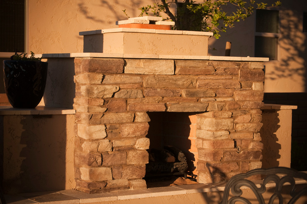Mid-sized mediterranean backyard patio in Phoenix with a fire feature, natural stone pavers and a roof extension.